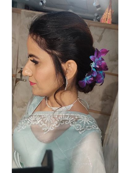 A sleek and elegant low bun decorated with purple orchids. This hairstyle is perfect for a reception or cocktail party and keeps the hair neatly off the face.