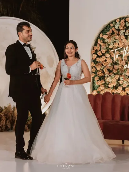 A romantic reception stage featuring a "To the moon and back" neon sign. Paired with a large moon prop and a floral arch, this design was a literal interpretation of the couple's love story.