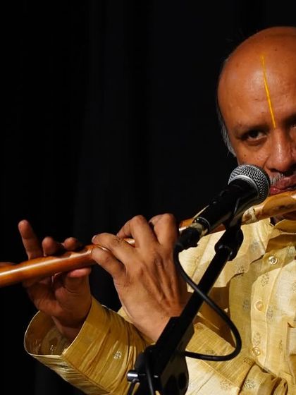 A close-up of our talented flutist during a performance. The flute adds a layer of melody and emotion that is essential to Carnatic music, and his skill was a highlight of the evening.