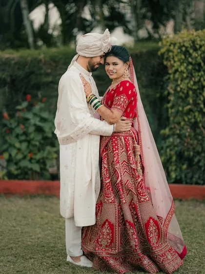 A classic portrait of a Maharashtrian couple in a garden, embracing and smiling, perfectly capturing their wedding day happiness.
