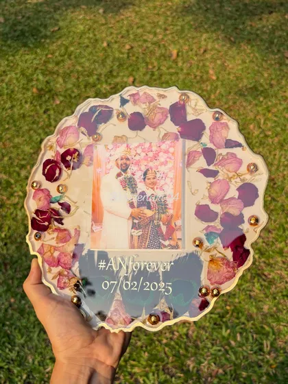 A geode-style resin plaque with preserved flowers, a wedding photo, and a custom hashtag. The irregular edge and gold details give it a modern and artistic feel.