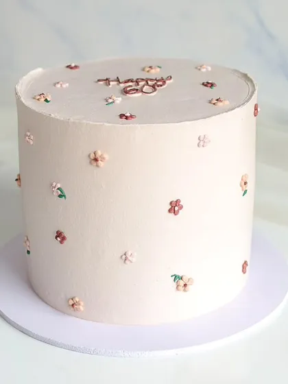 A tall, elegant cake in a neutral tone, decorated with tiny, hand-piped flowers. This minimalist design is perfect for a sophisticated 60th birthday celebration.
