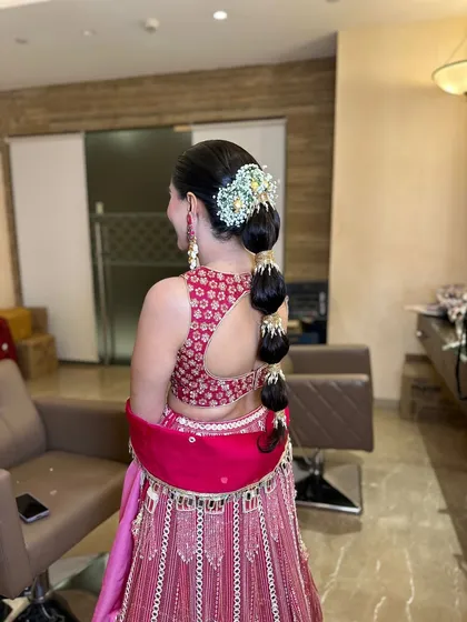 A modern and chic bubble braid, adorned with a stunning traditional hair accessory. This style is perfect for a Sangeet or Mehendi.
