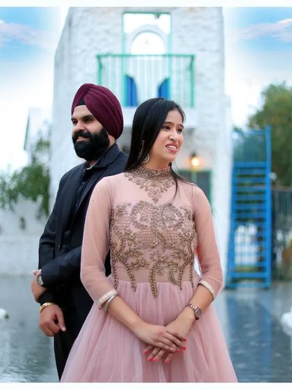 A beautiful pre-wedding portrait in a Santorini-style setting. The white and blue architecture provides a stunning and clean backdrop for the elegantly dressed couple.