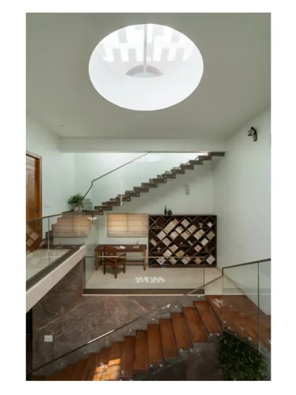 For this Bangalore home, I tucked a library and study nook into a mezzanine level. The floating stairs maintain a sense of openness, while the circular skylight above brings in focused natural light, making this a perfect, quiet corner for reading and work within a double-height space.