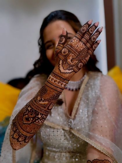 A playful "peek-a-boo" shot with a bride showing off her detailed palm and arm mehandi.
