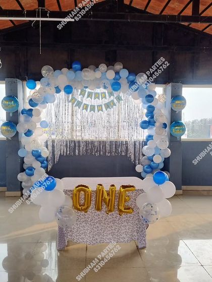 A simple and clean first birthday setup with a blue and white square balloon arch and a sequin-covered cake table.