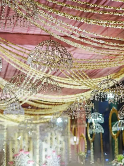A view of the ceiling decor, with layers of pink and gold fabric creating a soft, draped canopy. Hanging crystal umbrellas and floral tassels add to the enchanting, dreamlike feel.