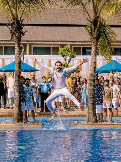 The groom making a splash with a jump into the pool, kicking off the pool party aspect of the celebration.