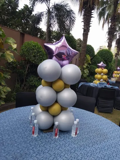 A stylish balloon centerpiece for a cocktail table. The combination of silver, gold, and a purple star foil balloon adds a touch of glamour to an outdoor event.