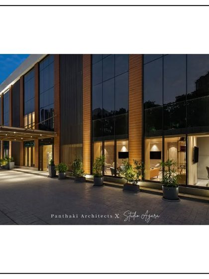 A dusk view of the office building facade. The warm interior lighting seen through the large windows contrasts with the cool evening sky, showcasing the building's active life.