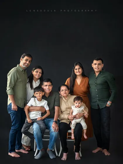 A full family portrait against a classic dark backdrop, creating a timeless and elegant look. The coordinated outfits in neutral tones help unify the image and keep the focus on their connection.