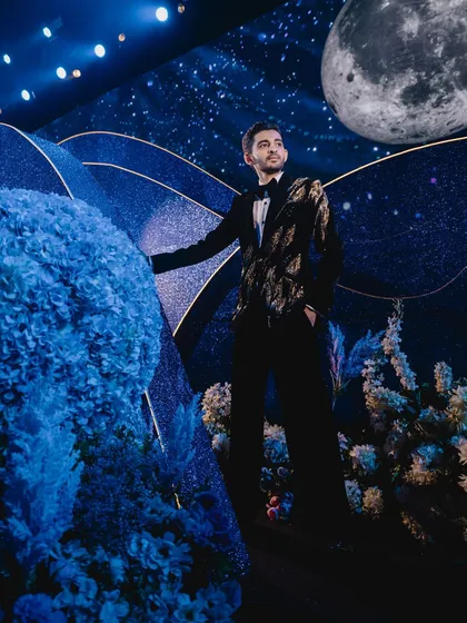 The groom is pictured against the celestial backdrop, with a large, realistic moon model hanging in the sky, adding to the authenticity of our created universe.