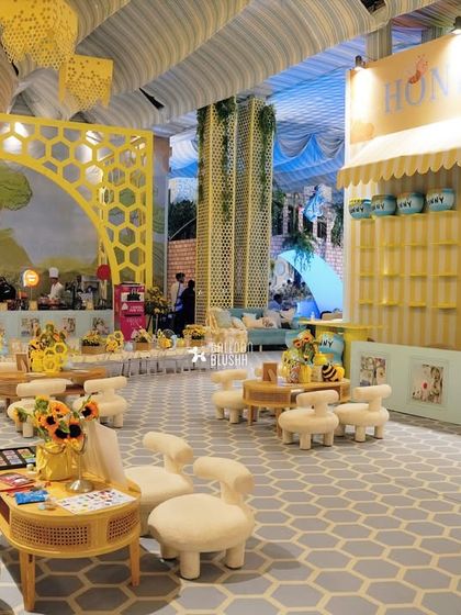 The 'Honey House' and seating area at the Winnie the Pooh party. The decor includes honeycomb-patterned backdrops, custom furniture, and sunflower arrangements.