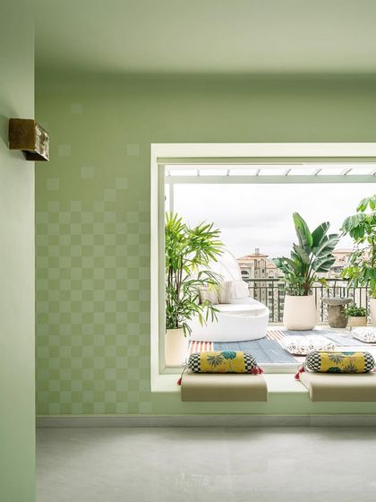 The family lounge, with its green checkered walls, opens up to a stunning outdoor view. This space was designed to feel like a warm hug, a comfortable spot for the family to relax and enjoy the simple joys.