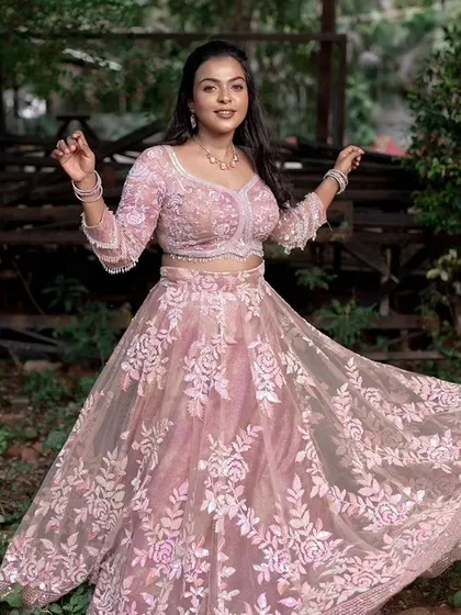 A full-length shot of a model in a pink lehenga, showing the beautiful twirl of the skirt.