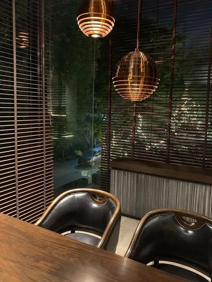 The view from the study at night, with the warm glow of the copper pendant lights reflecting in the large windows.
