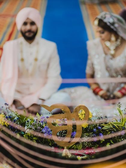 A beautifully composed shot of a Sikh couple during their Anand Karaj, framed by the decorated Palki Sahib.