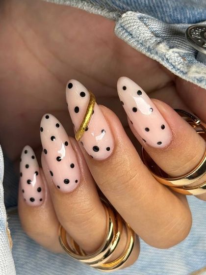 This photo perfectly captures the high-fashion aesthetic of our nail art, with the polka dot and gold design complementing the client's denim jacket and rings.