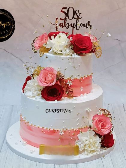A magnificent 4kg two-tier anniversary cake in pineapple flavor. This "50 & Fabulous" cake is decorated with real red and pink roses, carnations, and baby's breath.