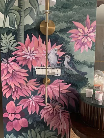 Here is a finished hand-painted nature mural that turns a living space into a tropical escape. We carefully paint around existing features like light fixtures and switches to make the art feel like a natural part of your home.