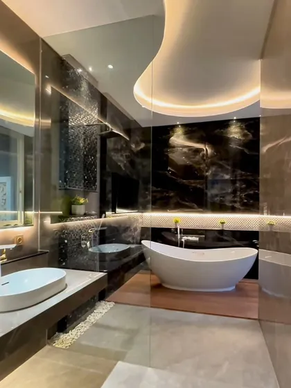 This master bathroom exemplifies our approach to creating a personal sanctuary. We used large format black marble slabs to create a glorious, seamless wall, juxtaposed with the warmth of a wooden platform for the freestanding tub. The custom-designed ceiling cove and backlit mirror provide layered, ambient lighting that enhances the mood while ensuring functional clarity.