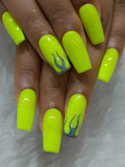 For those who love to be bold, we offer vibrant and playful designs like these neon flame nails. We used a bright, electric yellow gel polish on long square extensions and added a touch of silver glitter for the hand-painted flame details.