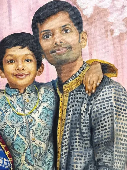 A close-up of the father and son from a family portrait, highlighting their matching traditional outfits.