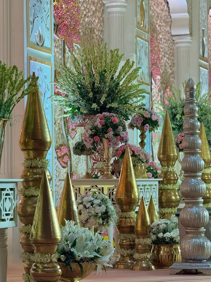 A detail shot of the traditional brass and silver decor pieces that line the stage. These elements, combined with fresh flowers, add a touch of royal grandeur.