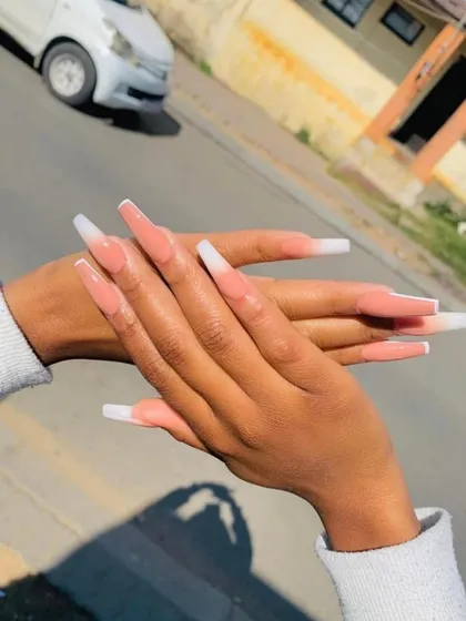A client photo showing off her long, coffin-shaped French ombre nails. This "baby boomer" style provides a seamless blend from pink to white for a softer look.
