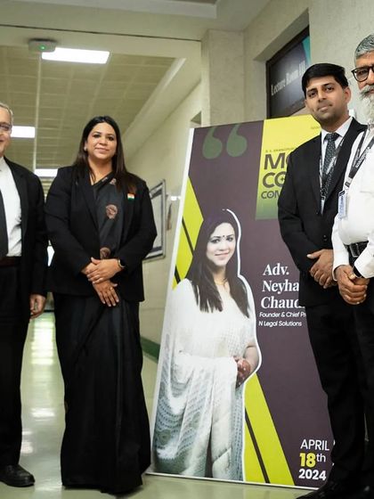 Standing with fellow judges next to a banner featuring my profile for the moot court competition. It is humbling to be featured as a guest and expert in these academic events.
