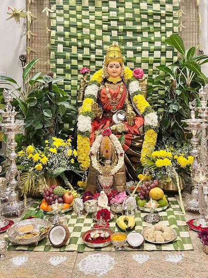 For this Varamahalakshmi pooja, the Goddess is draped in a radiant red and gold silk saree, symbolizing prosperity and auspiciousness.