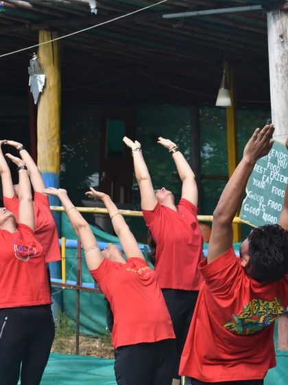 A group reaching upwards in a gentle backbend, soaking in the outdoor atmosphere during a yoga retreat.