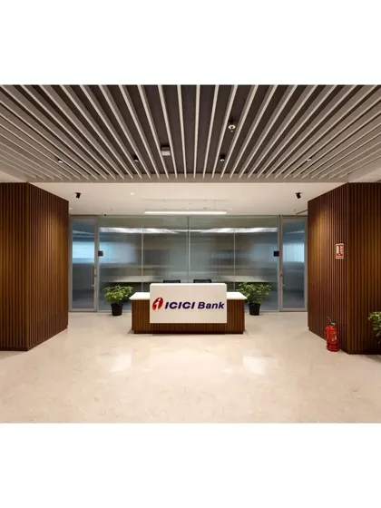 The primary reception desk at the ICICI Bank corporate office. We used a clean, minimalist desk design framed by rich, vertically slatted wood paneling and a louvered ceiling to establish a sense of structure and professionalism.