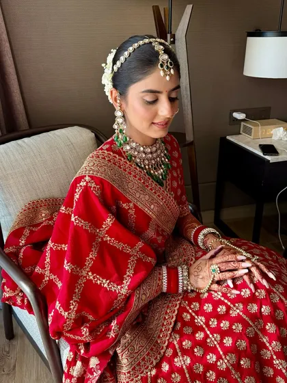 The complete bridal vision. Anmol's look features a classic hair bun with gajra, complementing the soft, traditional makeup for her wedding day.