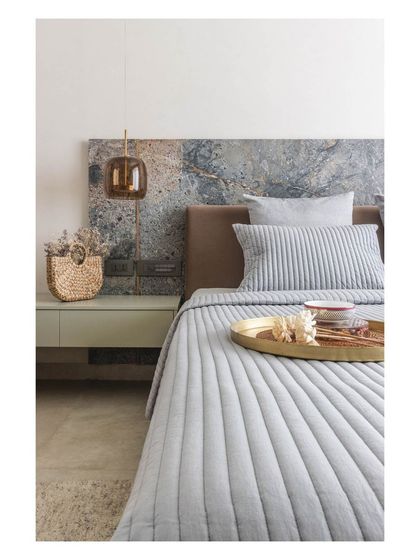 The texture and color variation in the marble headboard make it a true piece of art, anchoring the entire room.