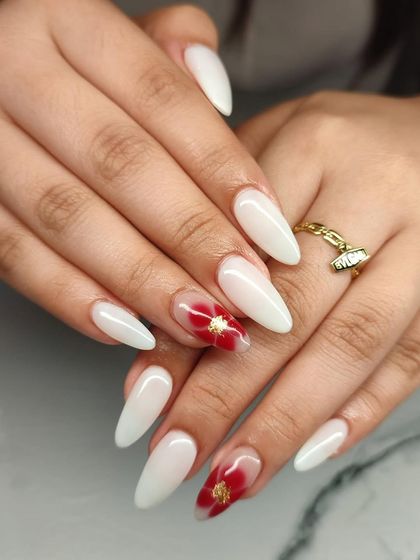 A beautiful and elegant set of milky white almond extensions with a striking red floral design on the accent nails.