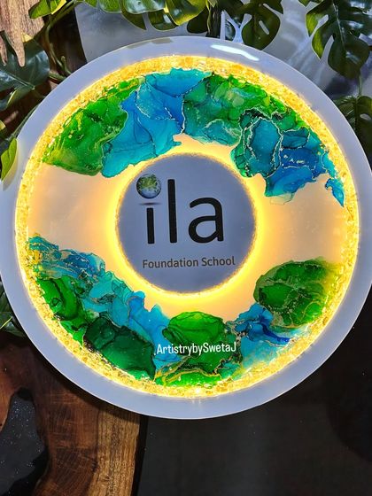 When art meets purpose. This lighted resin sign was created for a friend's new play school, featuring her logo surrounded by beautiful green and blue alcohol ink art.