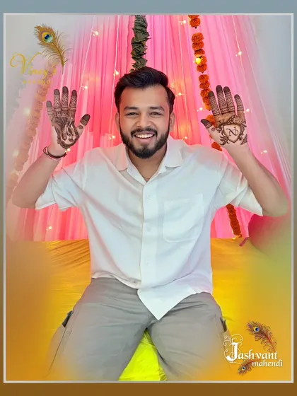 A happy groom raises his hands to show both of his unique mehndi designs.