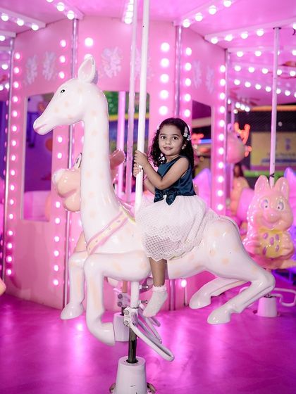 A whimsical shot from a first birthday party. The bright pink carousel creates a magical backdrop for this little girl's special day.