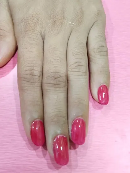 A classic, vibrant red-pink gel polish on medium-length nails. This is a timeless color that is both fun and elegant, suitable for any occasion.