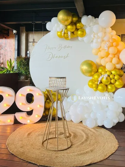 A clean and simple boho setup for a 29th birthday. The white and gold balloons, round jute rug, and marquee numbers create a bright and airy feel.