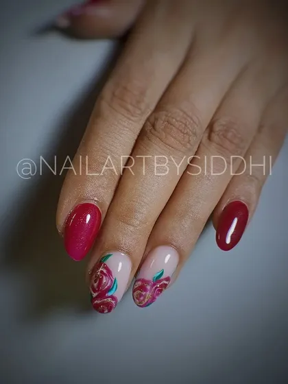 A classic red manicure with two accent nails featuring beautifully hand-painted roses.