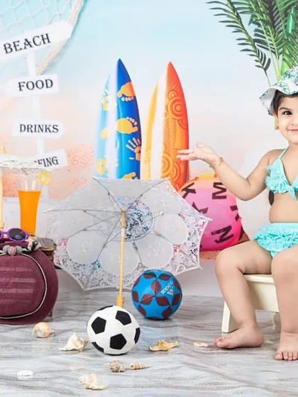 Life's a beach! This little girl is enjoying the sun and sand in my fun beach-themed setup, complete with surfboards and seashells.