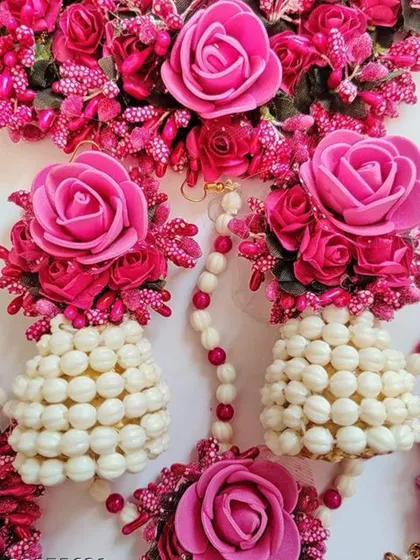A close-up of the jhumka-style floral earrings and necklace, showing the combination of artificial flowers and pearls.