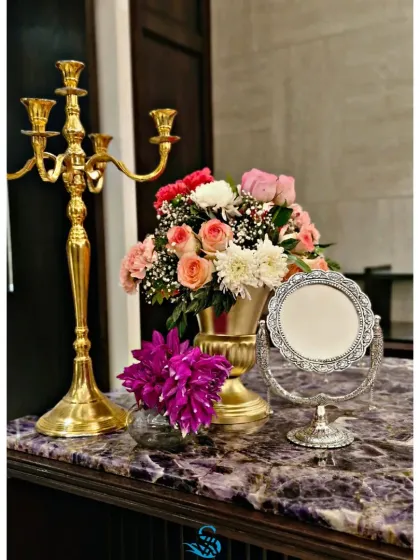 We pay attention to every corner. This console table vignette features a classic gold candelabra, a fresh floral arrangement, and an ornate silver mirror, adding a touch of vintage elegance to the event.