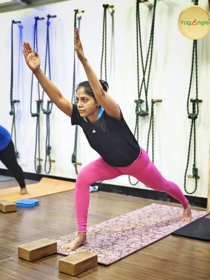 This dedicated student, who has been with us for over seven years, demonstrates a powerful Warrior 1 pose. Notice the use of blocks under her hands in a previous stage, a common technique we use to help students find the correct alignment before progressing.