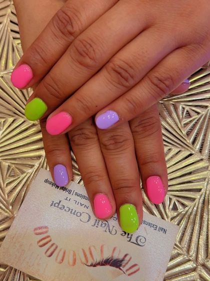 A fun and playful set of short, natural nails with a multi-color design. Each nail is painted a different solid pastel color, including pink, green, and purple.