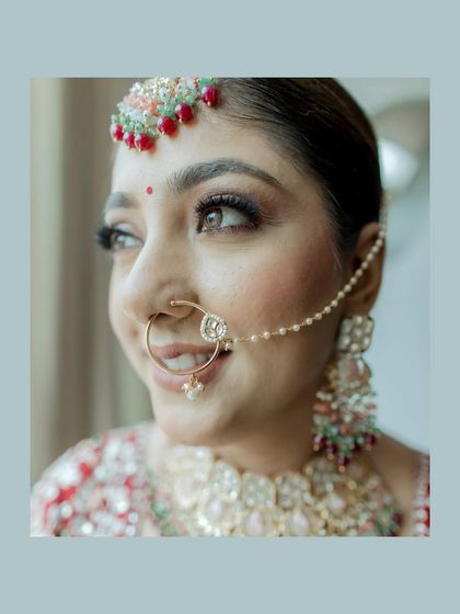 A beautiful close-up of the bride's face, highlighting her intricate nath and joyful smile. The soft color palette gives the portrait a gentle and warm feel.