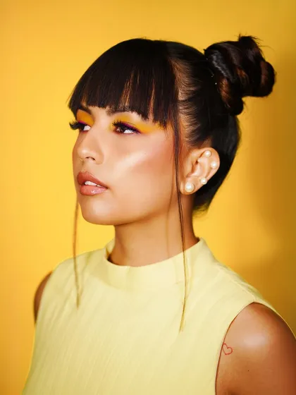 A close-up of the model's creative summer makeup, with bold yellow eyeliner and a high bun.